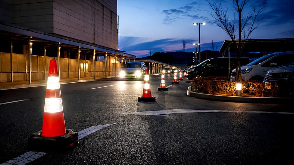 夜間や屋外駐車場で反射テープ付きカラーコーンと重石を使うイメージ
